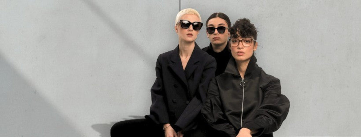 Three models wearing lavunett sunglasses and glasses in front of a concrete wall